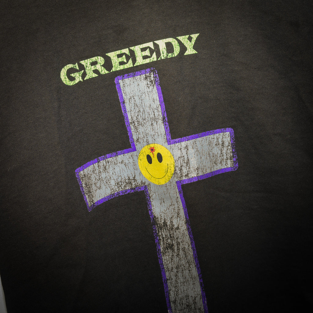 Greedy Unit tee close up of GREEDY lettering and bullet-hole smiley cross graphic