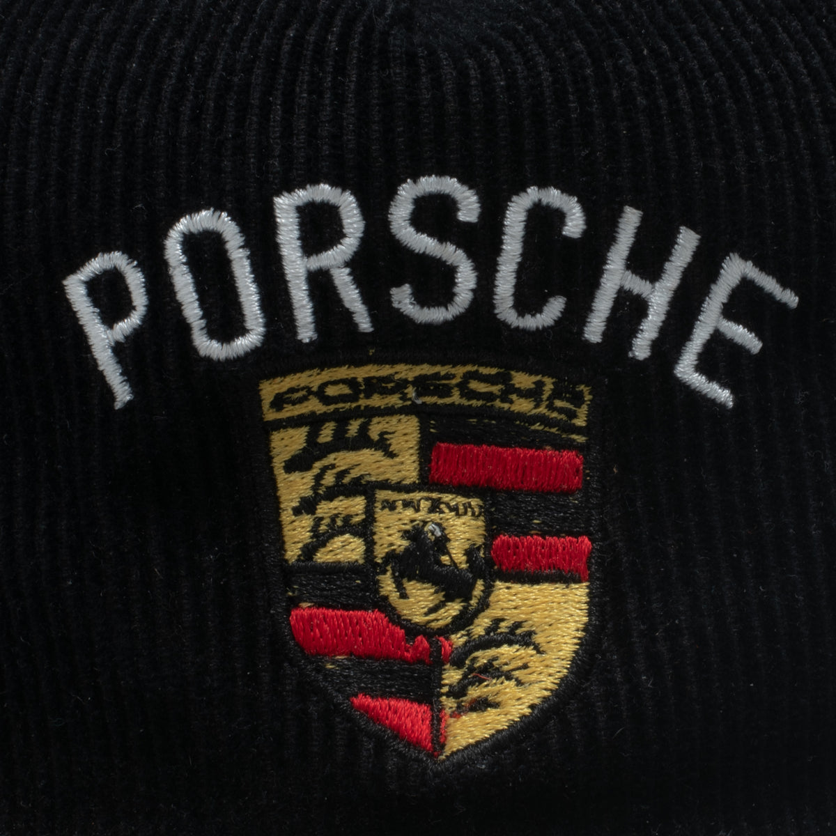 Vintage Porsche corduroy snapback hat embroidery close up showing full crest detail in gold and red
