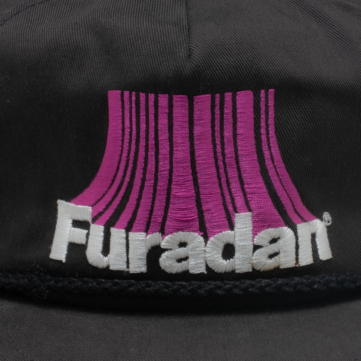 Vintage Furadan hat embroidery close up showing purple radiating stripe logo and white lettering