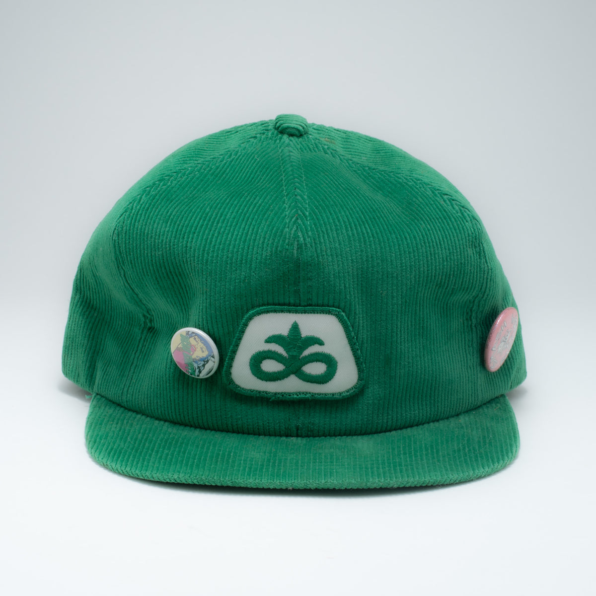 Vintage green corduroy snapback hat front view showing Pioneer Seeds patch and two vintage pins