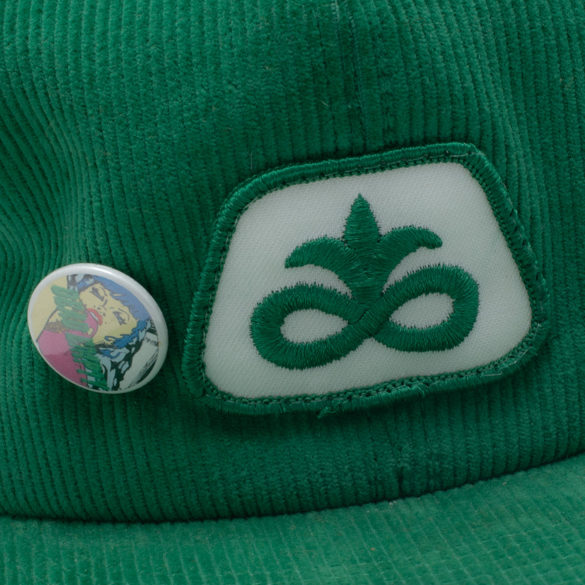 Vintage green corduroy snapback hat Pioneer Seeds patch and pop-art pin close up