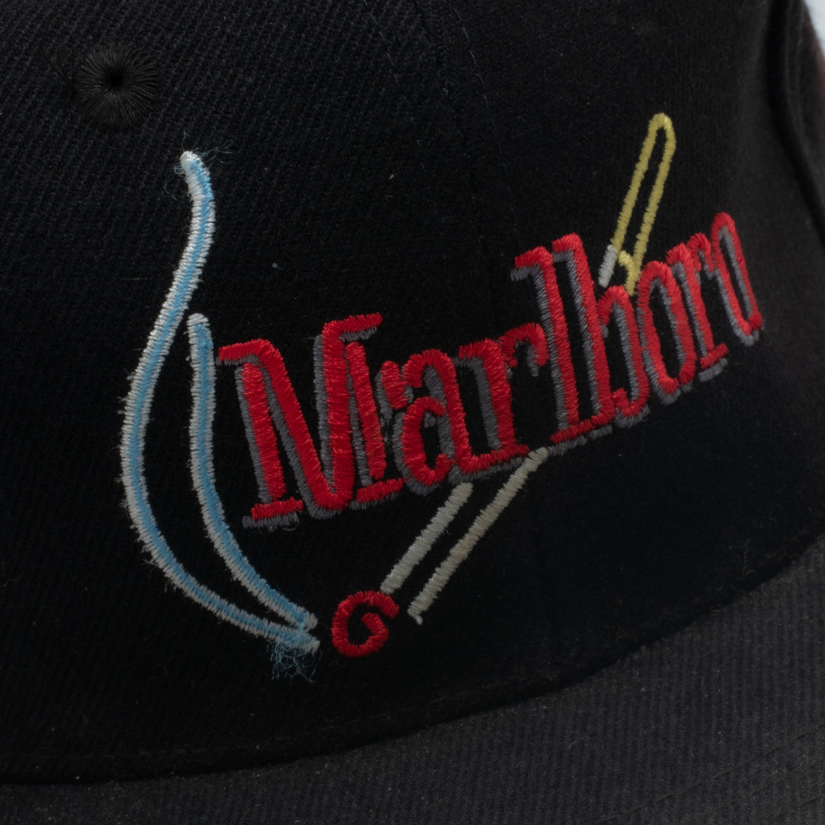 Vintage Marlboro cap embroidery close up showing red blue gold and grey script with smoke graphic