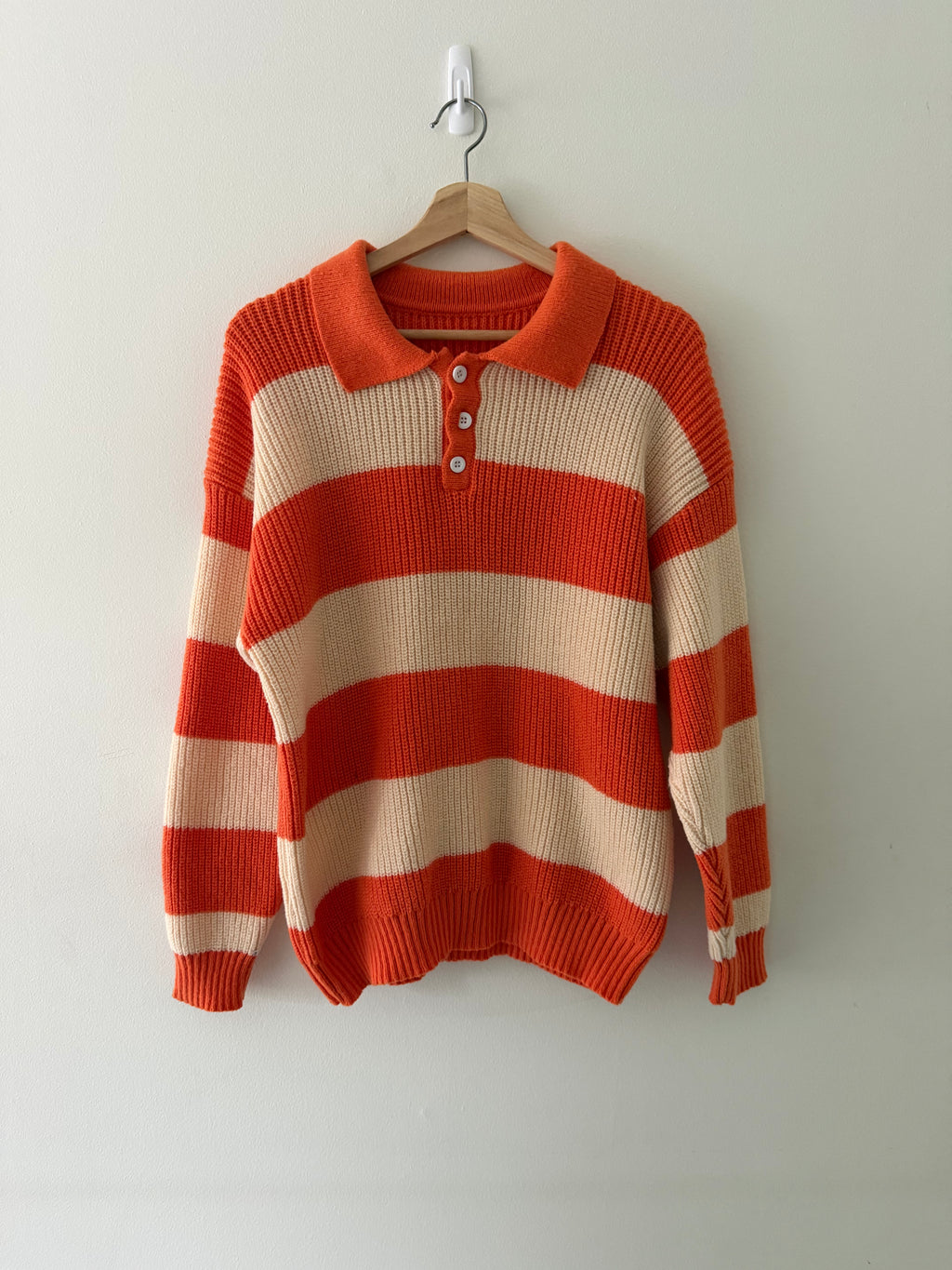 Vintage knit stripe polo sweater front view showing burnt orange and cream wide stripes and white shell buttons
