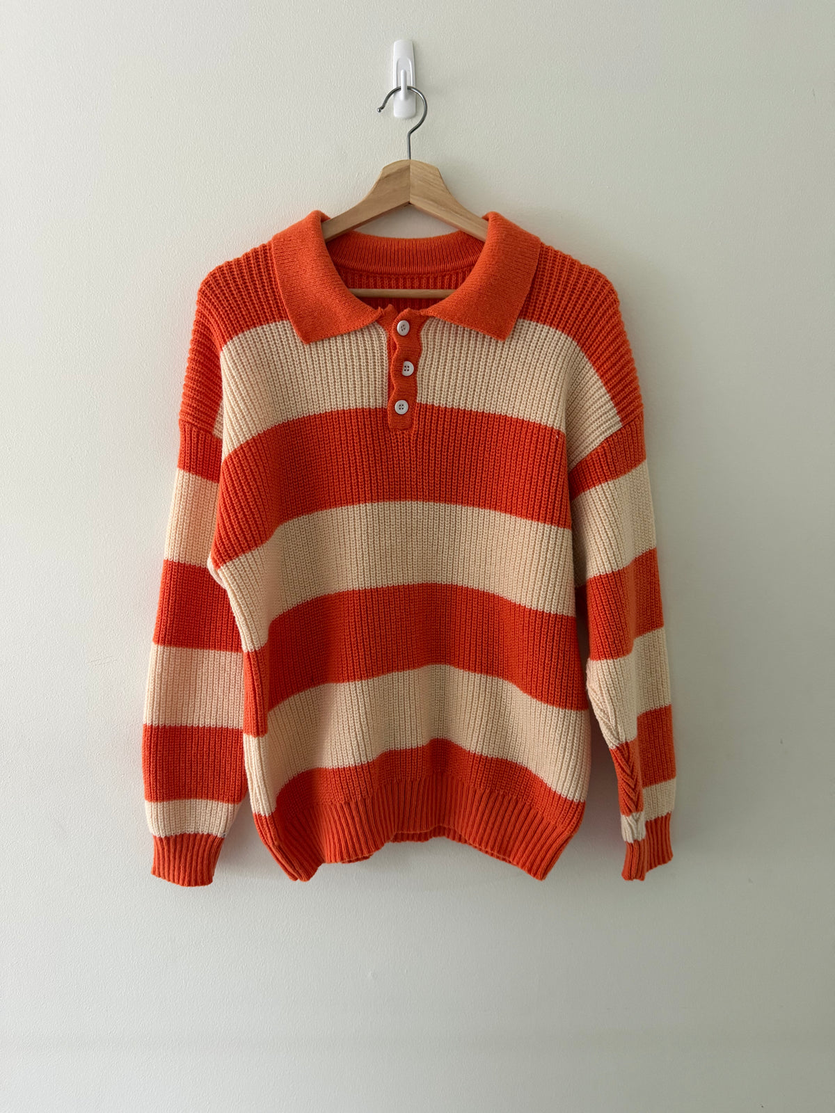 Vintage knit stripe polo sweater front view showing burnt orange and cream wide stripes and white shell buttons