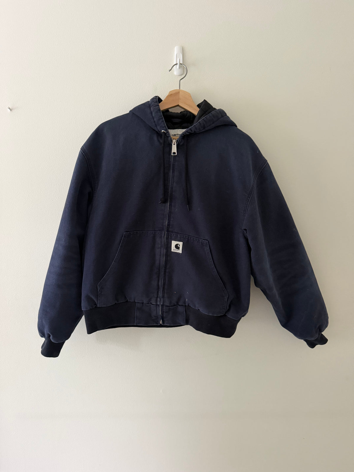 Vintage Carhartt WIP active hooded jacket front view in faded navy showing woven C patch and full zip