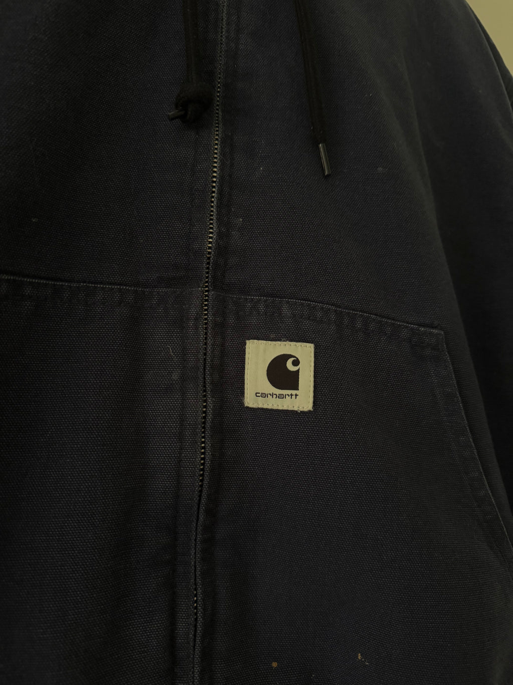 Carhartt WIP jacket close up of woven C patch on kangaroo pocket and canvas texture