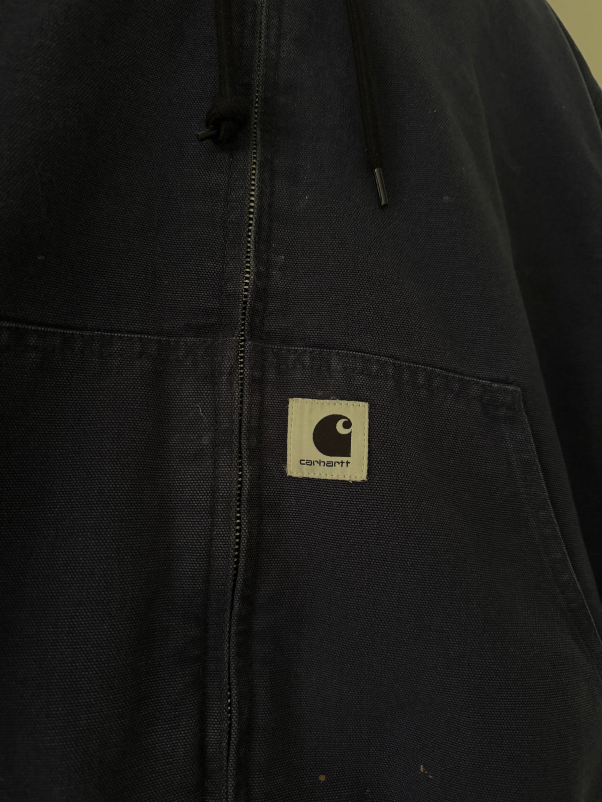 Carhartt WIP jacket close up of woven C patch on kangaroo pocket and canvas texture