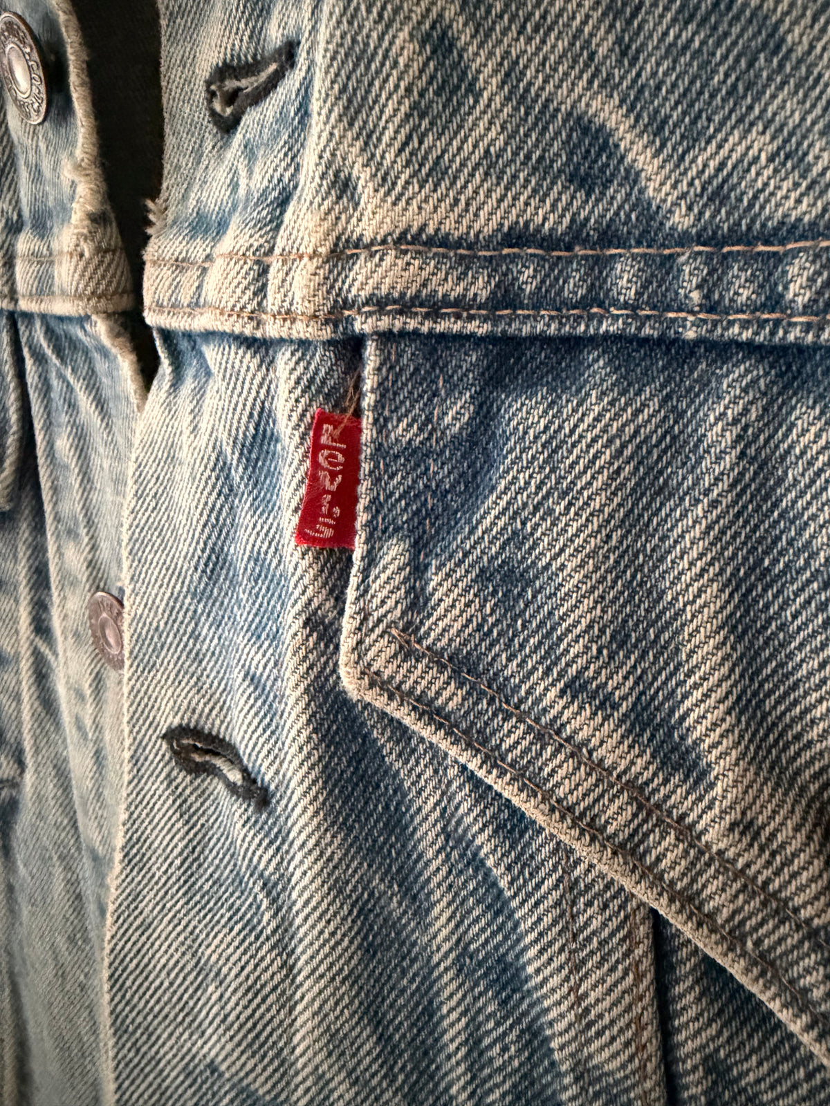 Vintage Levi's denim jacket close up of red Levi's tab on coin pocket with distressed denim detail