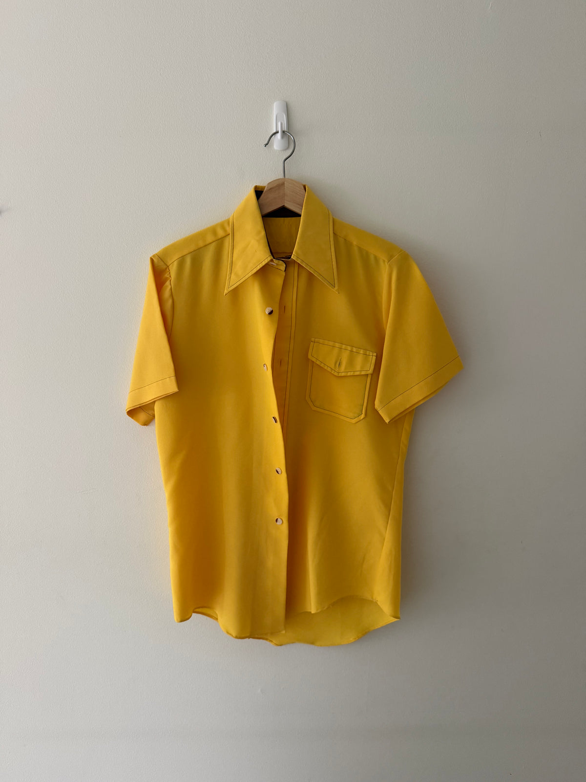Vintage 1970s canary yellow rayon short-sleeve button-up shirt full view on hanger