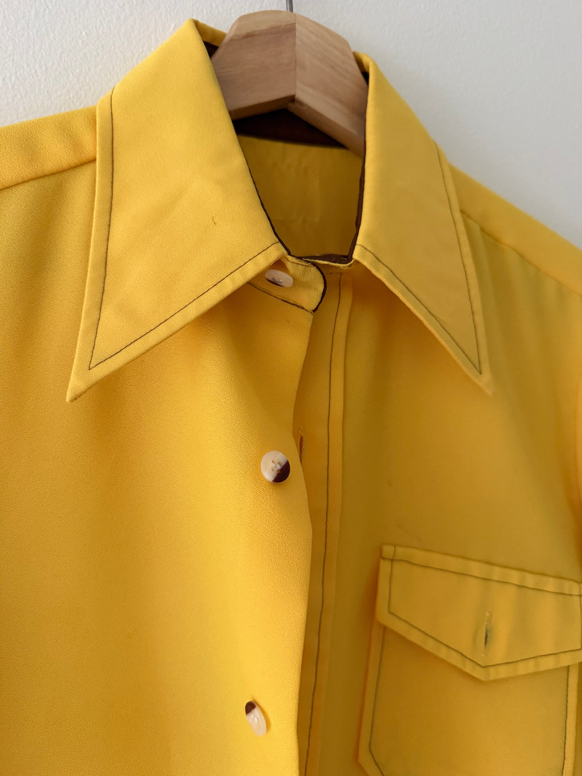 Vintage 1970s yellow rayon shirt close up of oversized pointed collar contrast topstitching and cream shell buttons