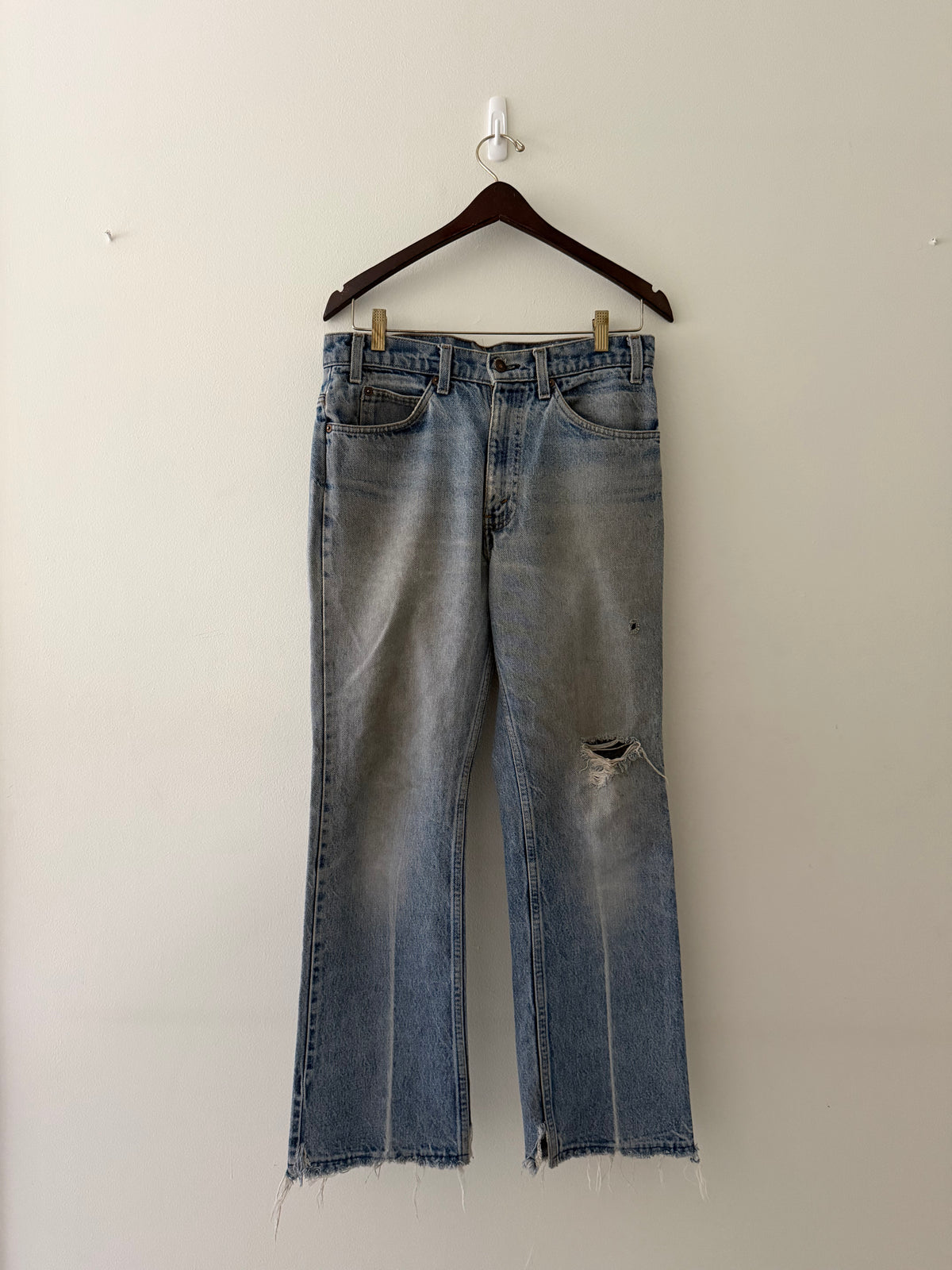 Vintage Levi's Orange Tab raw edge denim jeans full view showing blown-out knee hole and raw fraying hem