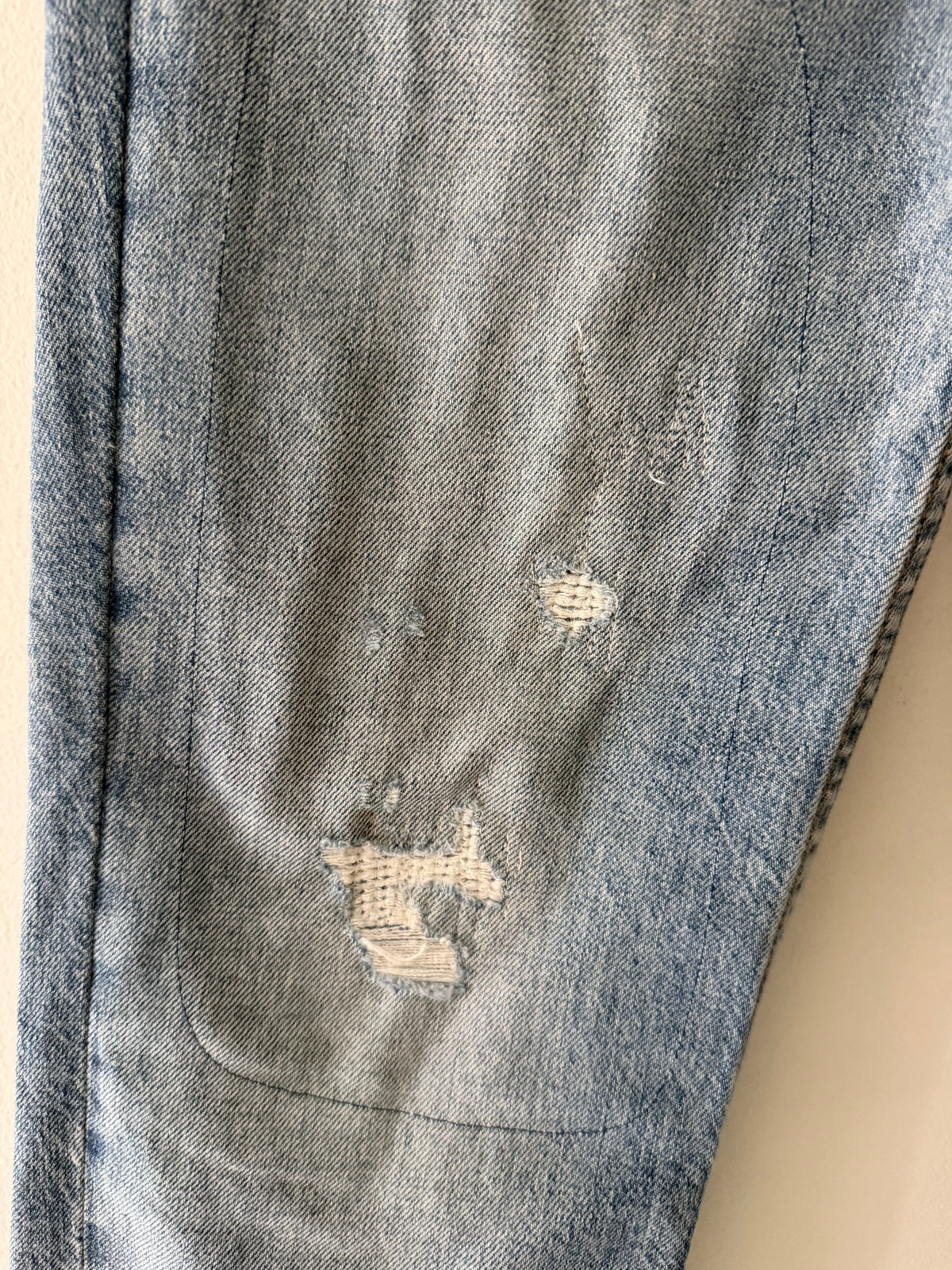 Vintage Levi's 511 right knee area close up showing small bullet hole with clear adhesive patch underneath