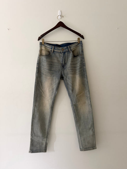 Dior mud-washed slim fit denim front view showing light blue wash with warm ochre tonal fading